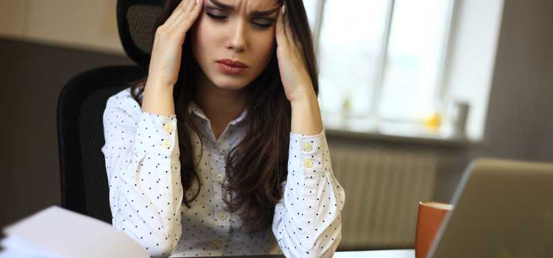 Woman looking stressed with books and a laptop.