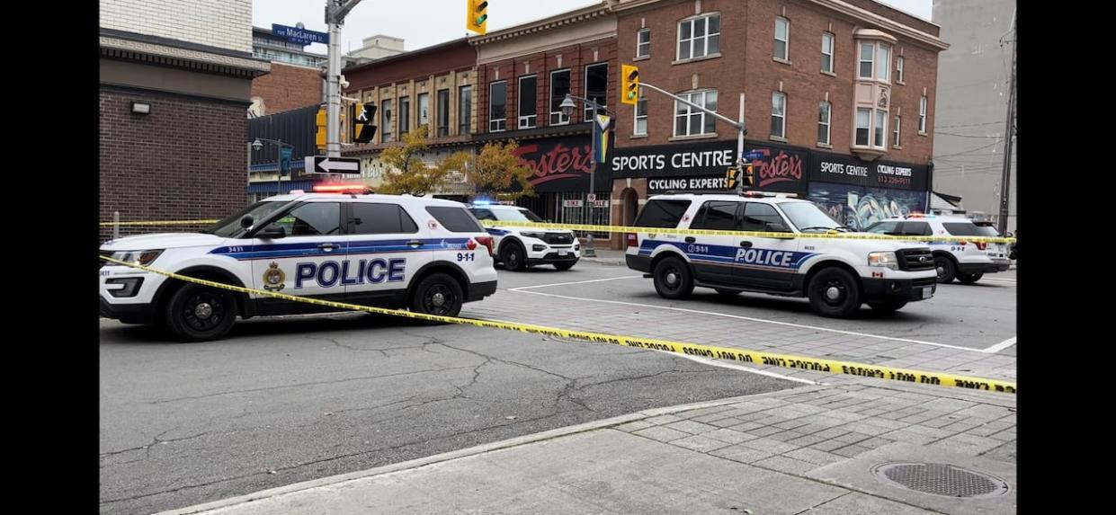 Police vehicles seen near Bank and Gilmour streets on Monday. Three people were charged and one of them remains in hospital with a gunshot wound. (Matthew Kupfer/CBC - image credit)