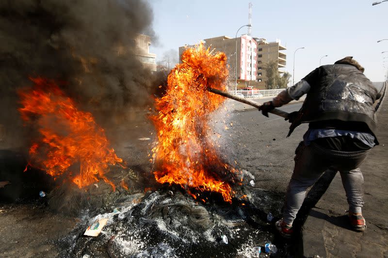 An Iraqi demonstrator burns tires to block a road during ongoing anti-government protests in Najaf,