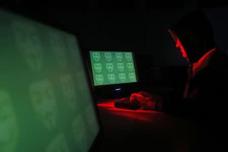 Man poses in front of on a display showing the word 'cyber' in binary code, in this picture illustration taken in Zenica December 27, 2014. REUTERS/Dado Ruvic