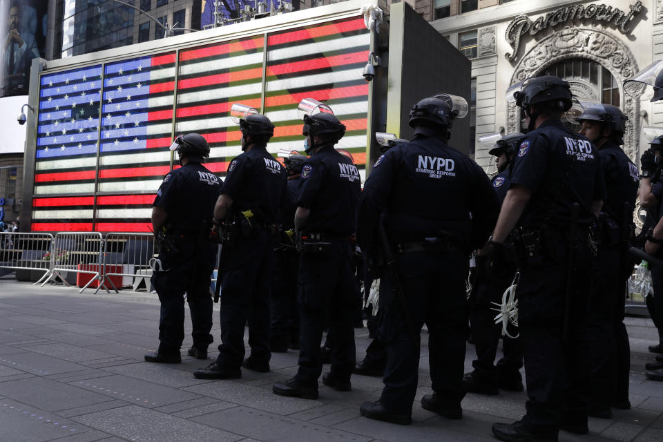 Police officers in riot gear stand by in Times Square during a protest in Manhattan in New York, Monday, June 1, 2020. New York City imposed an 11 p.m. curfew Monday as the nation's biggest city tried to head off another night of destruction erupting amid protests over George Floyd's death. (AP Photo/Seth Wenig)