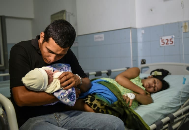 Venezuelan national Jose Luis Gonzales, holds his newborn as his wife Brecia Triago, rests at the Erasmo Meoz University Hospital in Cucuta, Colombia