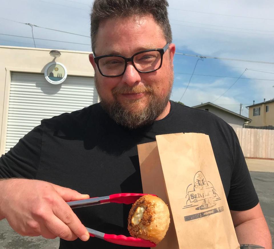 Salty Bagel owner Michael Milch bags up an order of his gluten-free bagels for a customer during a Friday afternoon pop-up at Avocado Shack in Morro Bay.