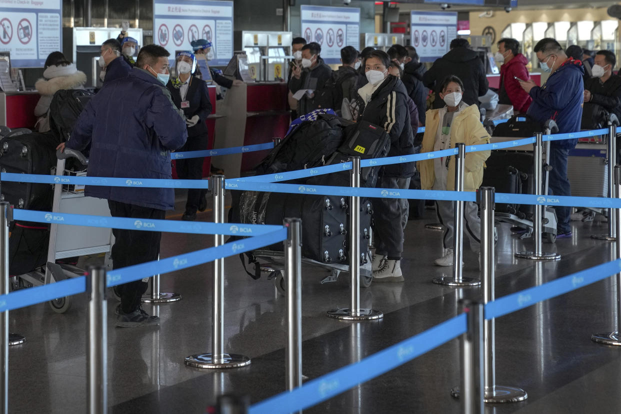 Masked travellers with luggage line up at the international flight check in counter at the Beijing Capital International Airport in Beijing, Thursday, Dec. 29, 2022. Moves by the U.S., Japan and others to mandate COVID-19 tests for passengers arriving from China reflect global concern that new variants could emerge in its ongoing explosive outbreak — and the government may not inform the rest of the world quickly enough. (AP Photo/Andy Wong)
