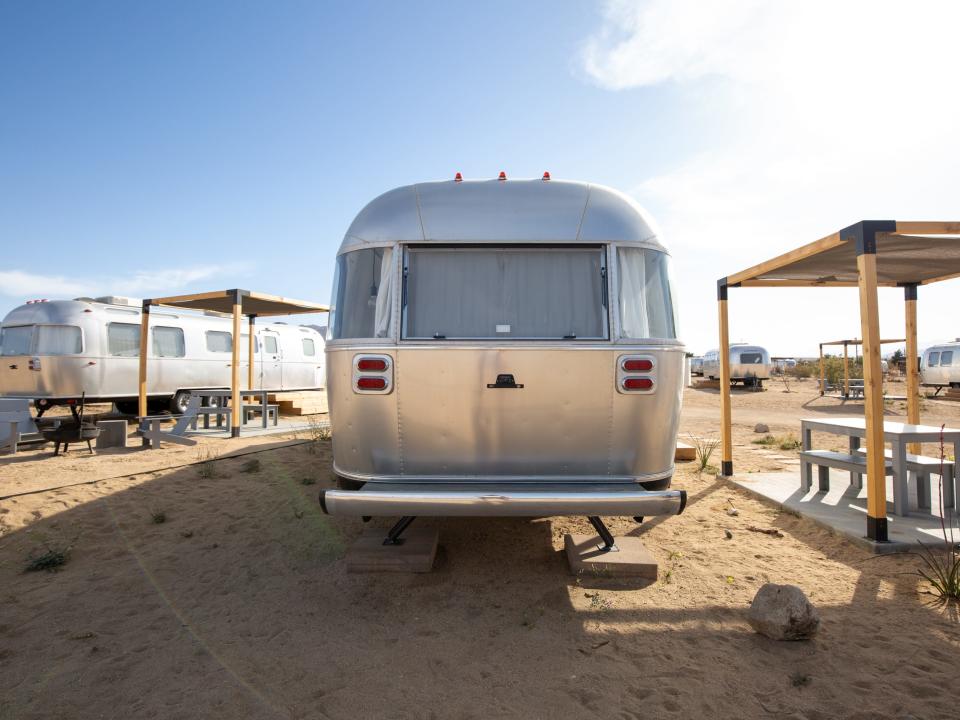 Airstream trailers outside at Autocamp's Joshua Tree location. There's tables and chairs between each trailer.