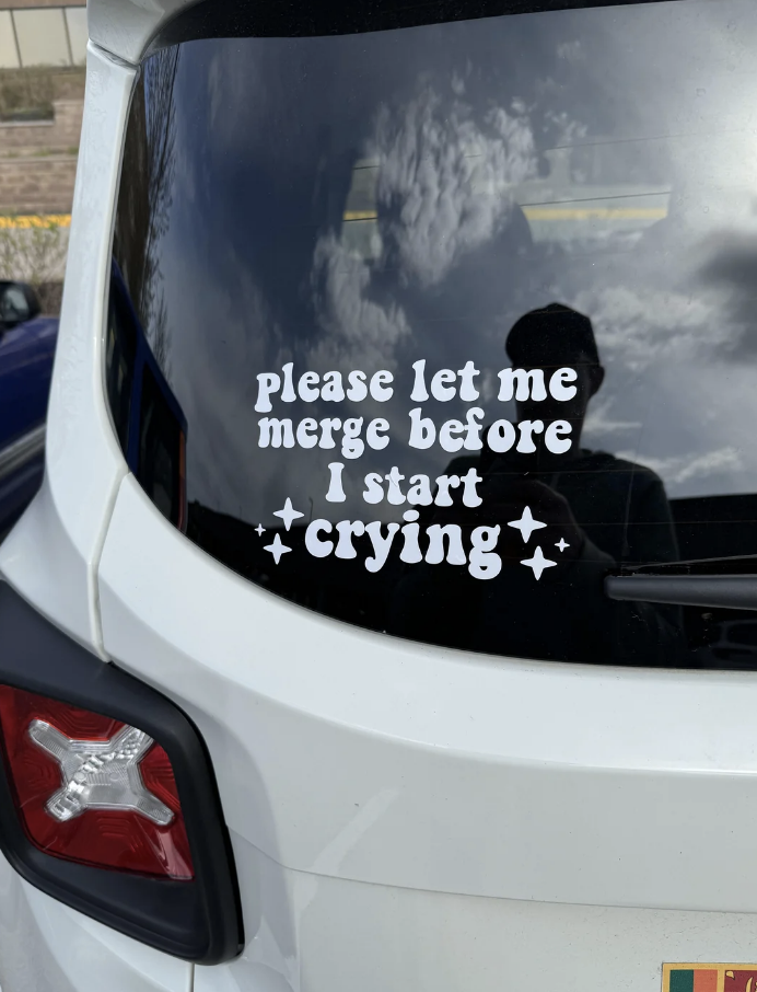 Rear window of a white car displaying a decal that reads, 
