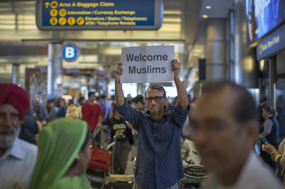Man holds a sign reading 'Welcome Muslims' in an airport