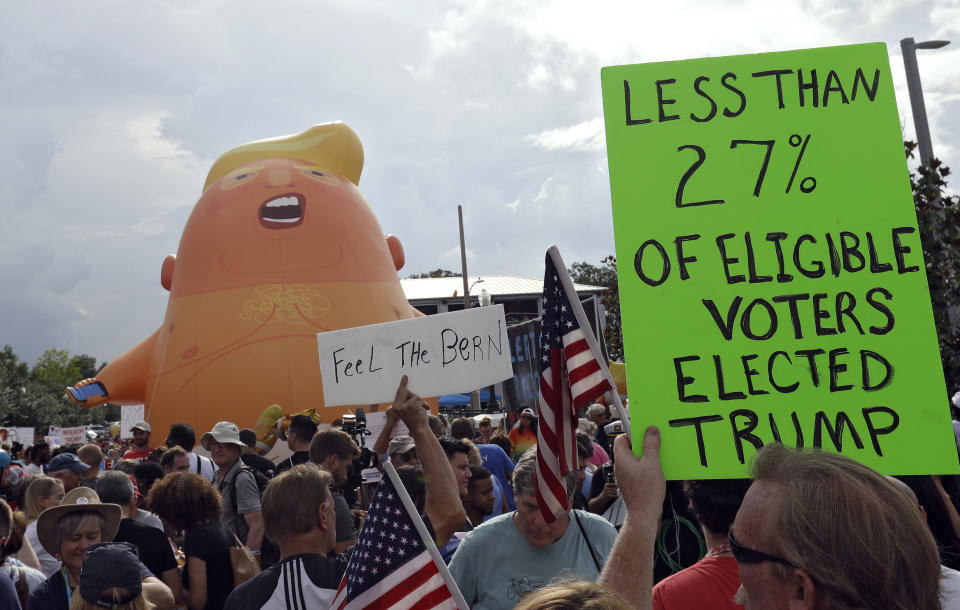 A group of protestors watch as a Baby Trump balloon is inflated during a rally Tuesday, June 18, 2019, in Orlando, Fla., near where President Donald Trump was announcing his re-election campaign. (AP Photo/Chris O'Meara)