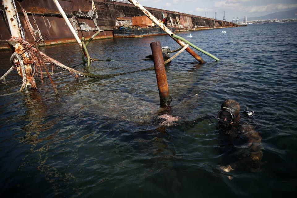A diver inspects a shipwreck during a raising operation, on Salamina island, west of Athens, on Wednesday, Feb. 13, 2020. Greece this year is commemorating one of the greatest naval battles in ancient history at Salamis, where the invading Persian navy suffered a heavy defeat 2,500 years ago. But before the celebrations can start in earnest, authorities and private donors are leaning into a massive decluttering operation. They are clearing the coastline of dozens of sunken and partially sunken cargo ships, sailboats and other abandoned vessels. (AP Photo/Thanassis Stavrakis)