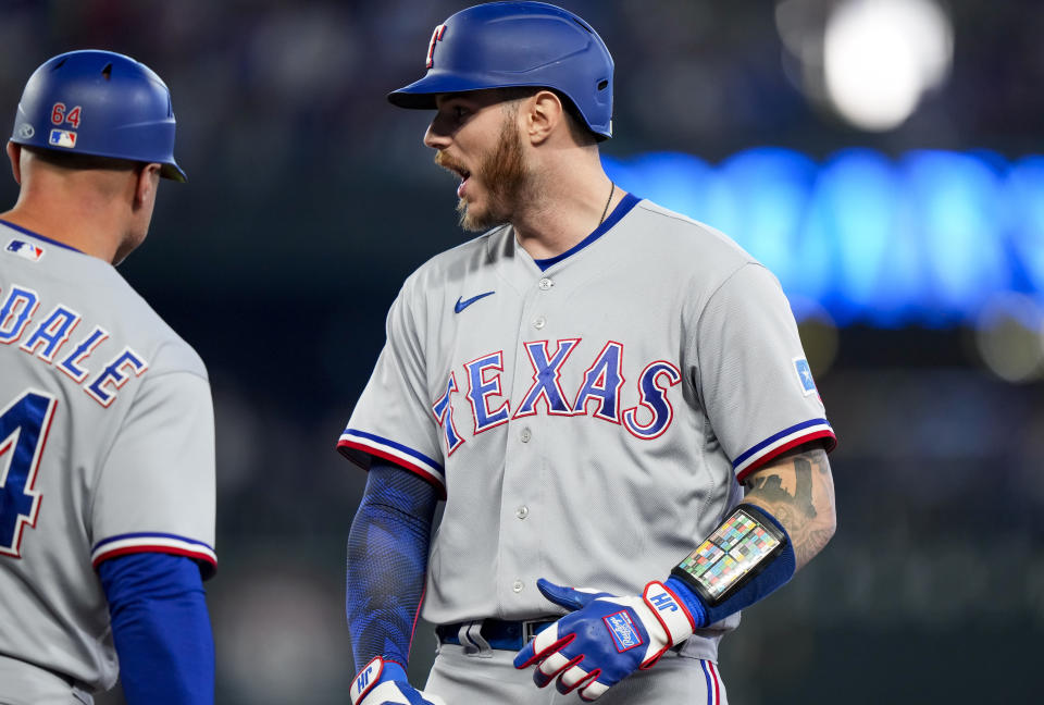 Texas Rangers' Jonah Heim reacts with first base coach Corey Ragsdale, left, after hitting a two-run single against the Seattle Mariners during the third inning of a baseball game, Saturday, Sept. 30, 2023, in Seattle. (AP Photo/Lindsey Wasson)