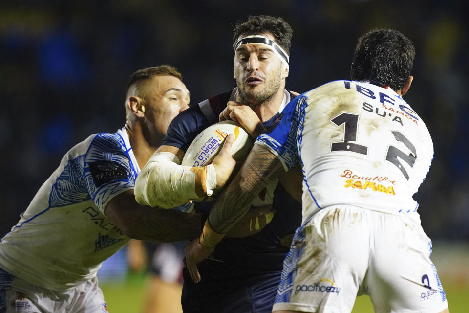 France's Benjamin Jullien, centre, is tackled by Samoa's Danny Levi, right, and Samoa's Jaydn Su'a during the Rugby League World Cup group A match between France and Samoa at the Halliwell Jones Stadium in Warrington, England, Sunday Oct. 30, 2022. (Mike Egerton/PA via AP)