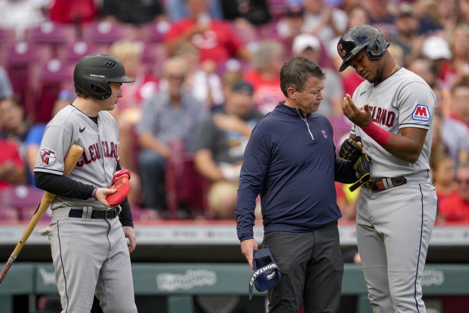 Cleveland Guardians' Oscar Gonzalez, right, is examined after being hit by a pitch during the first inning of a baseball game against the Cincinnati Reds in Cincinnati, Tuesday, Aug. 15, 2023. (AP Photo/Jeff Dean)