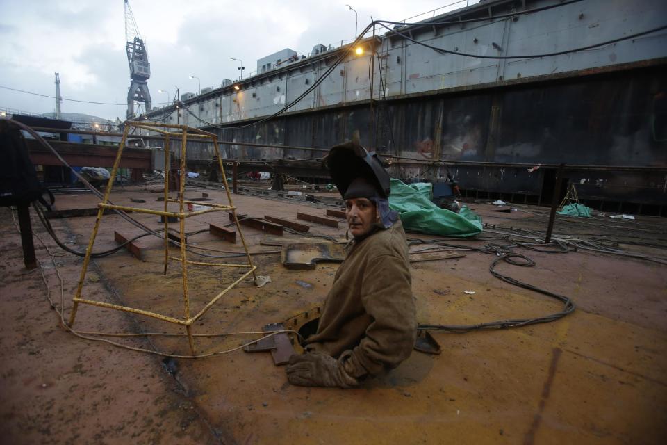 In this Wednesday, Feb. 12, 2014 photo a worker comes out from a dry dock's access hole at a shipyard in the depressed Perama area, on the fringes of Athens' port of Piraeus. For Perama, the ships have sailed. Until recently, this working class town at Athens’ western tip hosted some of the busiest shipyards in Greece, a maritime country with one of the world’s biggest shipping industries. Perama’s unemployment is among the worst in Greece, where the nationwide figure for November was 28 percent, according to the statistical authority on Thursday, Feb. 13, 2014. (AP Photo/Thanassis Stavrakis)