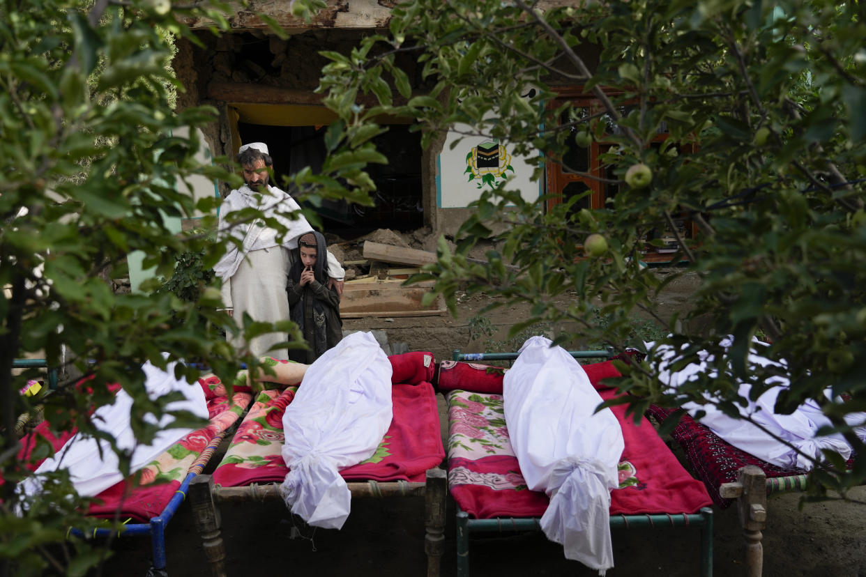 Afghans stand by the bodies of relatives killed in an earthquake in Gayan village, in Paktika province, Afghanistan, Thursday, June 23, 2022. A powerful earthquake struck a rugged, mountainous region of eastern Afghanistan early Wednesday, flattening stone and mud-brick homes in the country's deadliest quake in two decades, the state-run news agency reported. (AP Photo/Ebrahim Nooroozi)