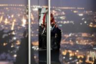 Protesters are reflected on the door of a closed shop as the storefront is covered with a photograph of Athens by night during a rally against unemployment and austerity on Thursday, March 27, 2014. After a deep recession that started in 2008, Greece is widely predicted to start growing, albeit modestly, but the ground to be made up is huge, with the Greek economy nearly a quarter smaller than it was and unemployment at more than 27 percent. The crisis has also seen hundreds of thousands of Greeks lose their state-backed health insurance, as most benefits expire after a year of unemployment. (AP Photo/Thanassis Stavrakis)