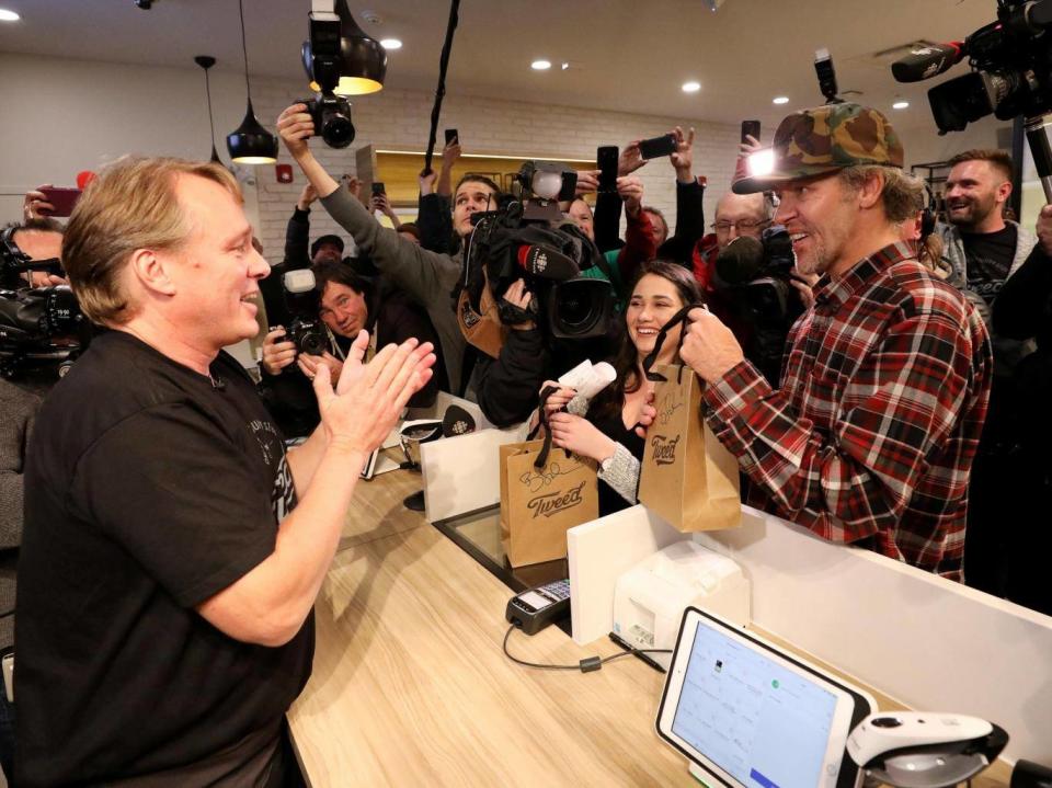 Canopy Growth CEO Bruce Linton hands Ian Power and Nikki Rose the first legal recreational marijuana purchases after midnight at a store in St John's, Newfoundland and Labrador, Canada (REUTERS)