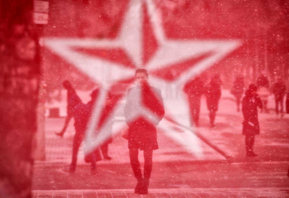 FILE- In this Saturday, Feb. 23, 2019 file photo, seen through the mesh covering of an electoral advertising point for the Socialits' Party, people walk in Chisinau, a day before the country holds parliamentary elections. A Moldovan court has appointed former prime minister Pavel Filip as interim president, a day after a new government was formed following a months-long political stalemate. The Constitutional Court said Sunday, June 9 that Igor Dodon, who supported the new government, was being relieved of his duties for failing to comply with its ruling to dissolve parliament.(AP Photo/Vadim Ghirda, file)