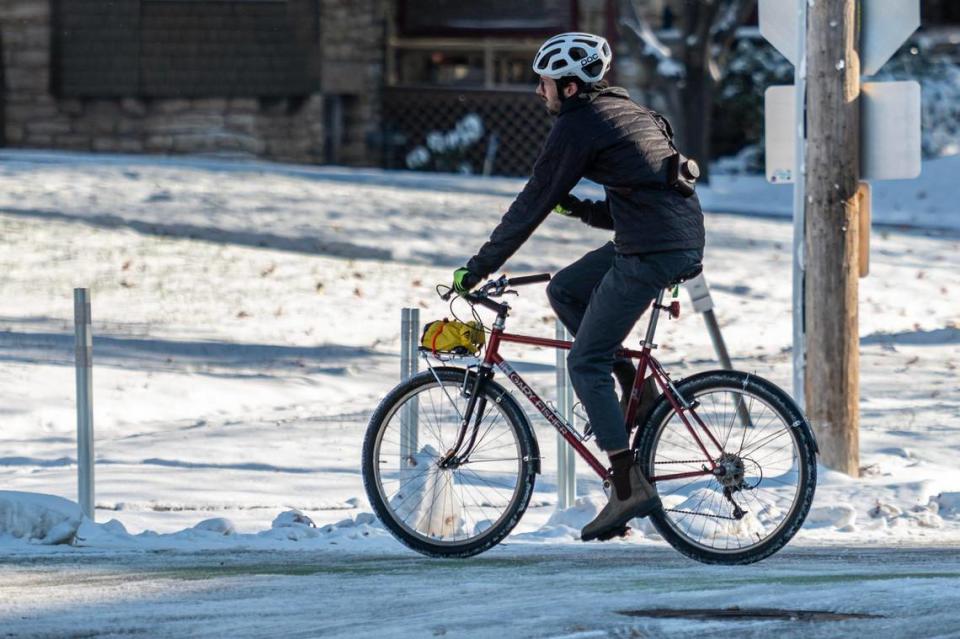 A cyclist rides a bike through the snow along Gillham Road following Kansas City’s first snowfall of the season on Sunday, Nov. 26, 2023.