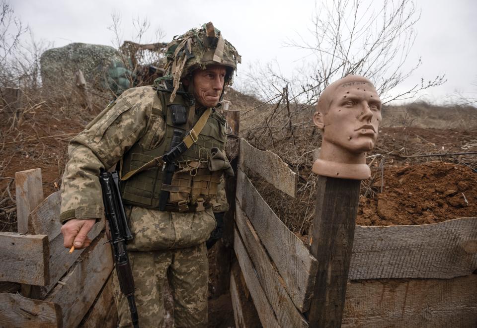 A Ukrainian soldier walks in a trench at the line of separation from pro-Russian rebels, Donetsk region, Ukraine, Sunday, Jan. 9, 2022.