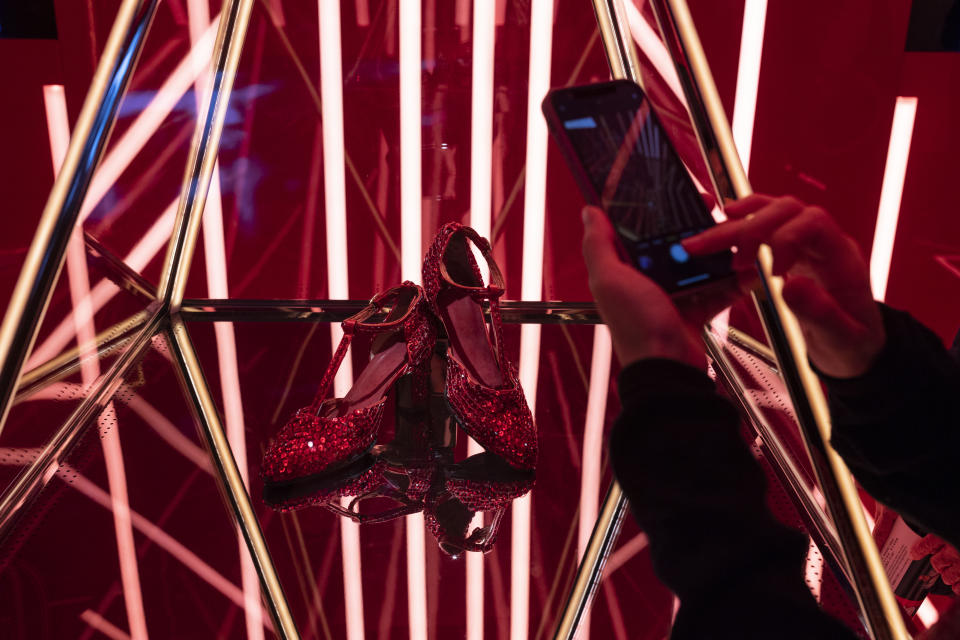 Visitors take photographs of the red high heels worn by Leslie Cheung at a concert in 1997 at an exhibition commemorating the 20th anniversary of the death of Canto-pop singer Leslie Cheung in Hong Kong, Wednesday, March 29, 2023. (AP Photo/Louise Delmotte)