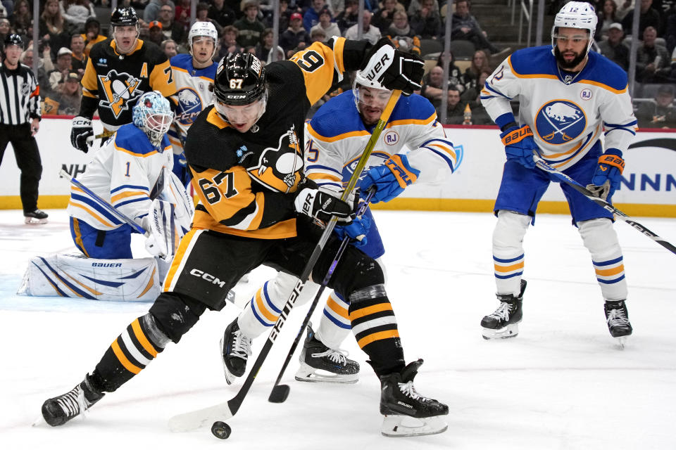 Pittsburgh Penguins' Rickard Rakell (67) controls the puck with Buffalo Sabres' Connor Clifton, center right, defending during the second period of an NHL hockey game in Pittsburgh, Saturday, Nov. 11, 2023. (AP Photo/Gene J. Puskar)