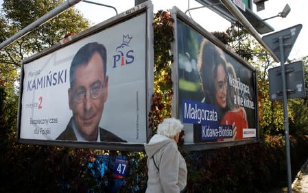 A woman walks in front of election banners in Warsaw
