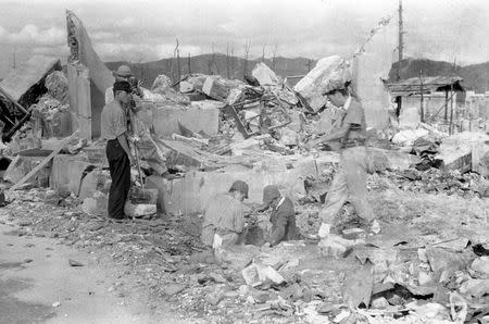 Survey team members measure residual radiation in the ruins of Shima Hospital, located at the hypocenter of the atomic bombing of Hiroshima on August 6, 1945, as Japan Film Corporation staff film them in Saiku-machi district in Hiroshima, Japan, in this handout photo taken by Shigeo Hayashi in October 1945 and released by the Hiroshima Peace Memorial Museum. REUTERS/Shigeo Hayashi/Hiroshima Peace Memorial Museum/Handout via Reuters