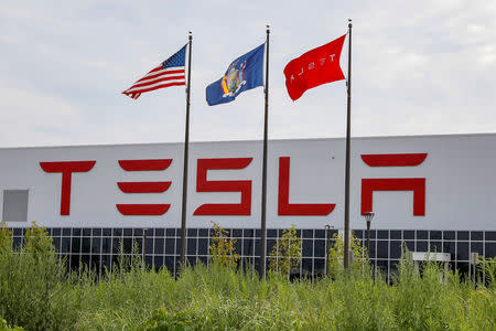 FILE PHOTO: Flags fly over the Tesla Inc. Gigafactory 2, also known as RiverBend, a joint venture with Panasonic to produce solar panels and roof tiles in Buffalo, New York, U.S., August 2, 2018. REUTERS/Brendan McDermid/File Photo