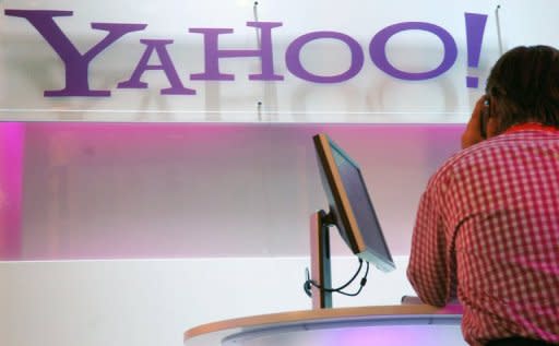 A visitor sits next to a laptop near the logo of Yahoo at a trade fair in Germany. Facebook and Yahoo! announced Friday a new advertising partnership as the two tech giants settled a court dispute over patents