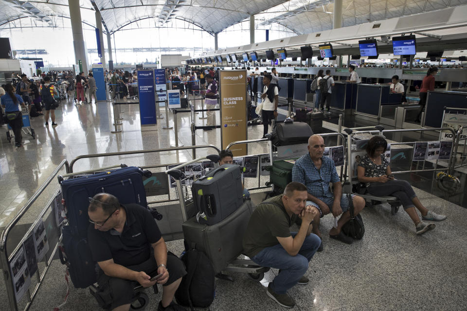 Travelers wait at the check-in counters in the departure hall of the Hong Kong International Airport in Hong Kong, Tuesday, Aug. 13, 2019. Protesters clogged the departure area at Hong Kong's reopened airport Tuesday, a day after they forced one of the world's busiest transport hubs to shut down entirely amid their calls for an independent inquiry into alleged police abuse. (AP Photo/Vincent Thian)