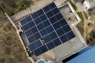 Workers of Solar Square put up a panel on the rooftop of a residence in Gurugram on the outskirts of New Delhi, India, Tuesday, Feb. 20, 2024. India is renewing its push to add rooftop solar to meet the needs of a fast-growing nation that's hungry for energy. (AP Photo/Manish Swarup)