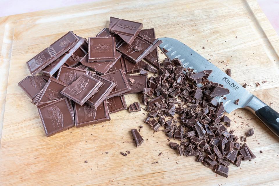 cubes of chocolate chobbed up on a cutting board with a knife