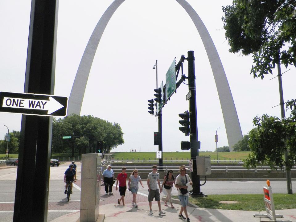 Pedestrians cross a street near the iconic Gateway Arch in St. Louis.