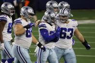 Dallas Cowboys' Brandon Knight (69) and Tyler Biadasz (63) walk off the field with running back Ezekiel Elliott (21) after Elliott fumbled the ball on a carry against the Arizona Cardinals in the first half of an NFL football game in Arlington, Texas, Monday, Oct. 19, 2020. (AP Photo/Ron Jenkins)