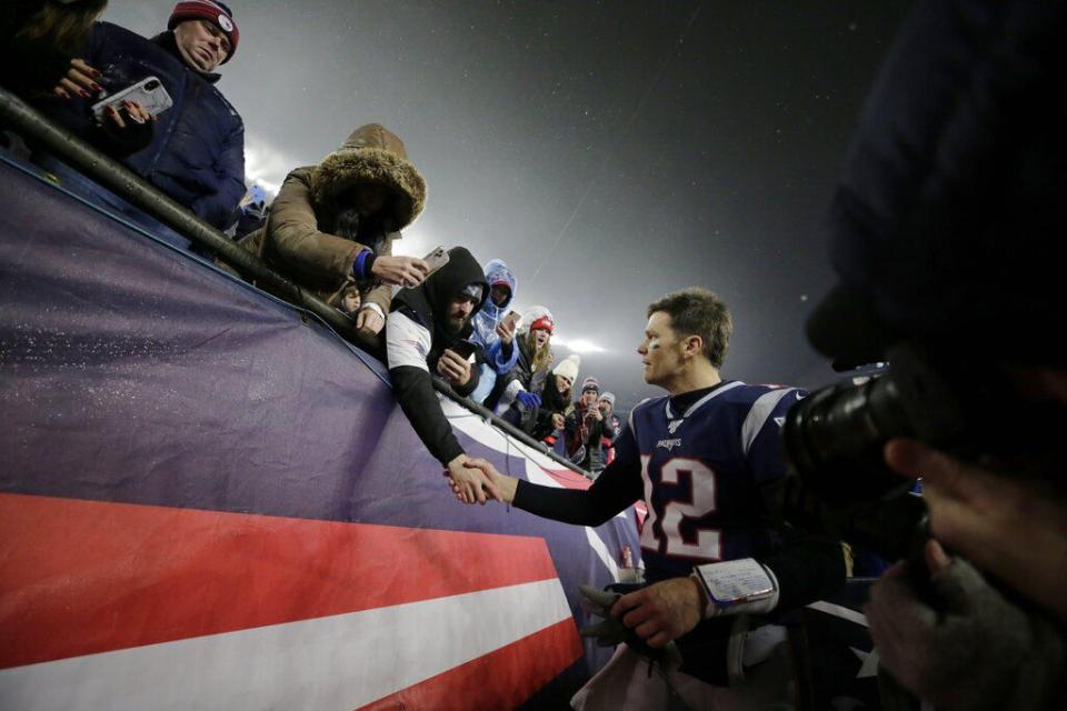 FILE - New England Patriots quarterback Tom Brady shakes hands with a fan as he leaves the field after losing an NFL wild-card playoff football game to the Tennessee Titans in Foxborough, in this Saturday, Jan. 4, 2020, file photo. Brady hasn't played an NFL football game in New England since Jan. 4, 2020. But remnants from his 20-year run with the Patriots remain everywhere in Foxborough. (AP Photo/Charles Krupa, File)