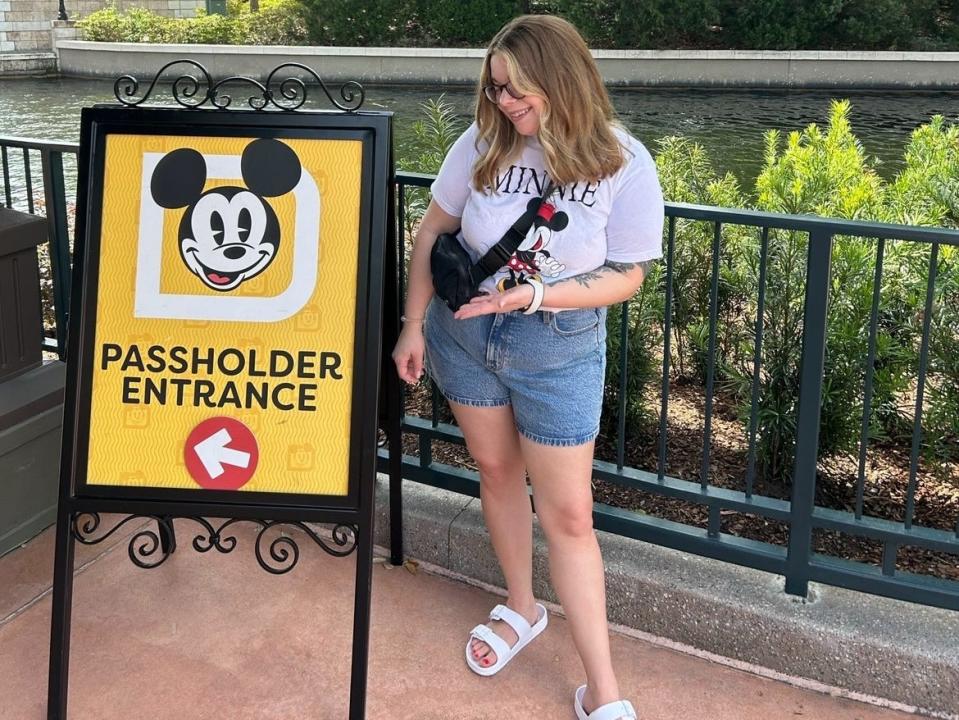 Jacqueline pointing to a sign that says "Passholder Entrance," with a picture of Mickey Mouse and an arrow pointing left.