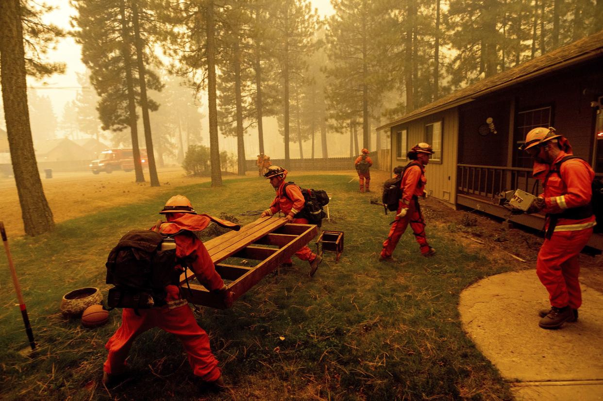 Inmate firefighters prep a home by moving combustible items as the Dixie Fire burns in Chester, Calif., on Wednesday, Aug. 4, 2021. The region is under red flag fire warnings due to dry, windy conditions.