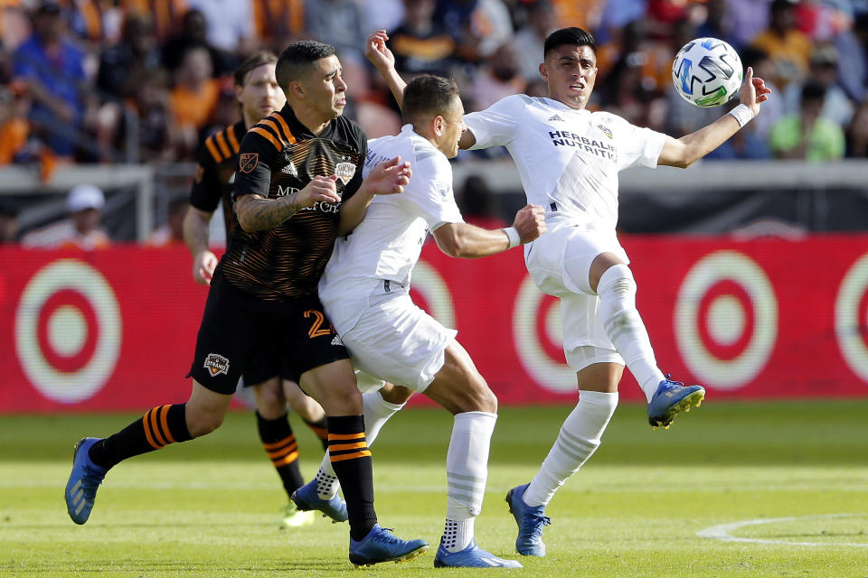 Houston Dynamo midfielder Matías Vera, left, is blocked out by LA Galaxy forward Javier "Chicharito" Hernandez, middle, as midfielder Joe Corona, right, kicks the ball away during the second half of an MLS soccer match Saturday, Feb. 29, 2020, in Houston. (AP Photo/Michael Wyke)