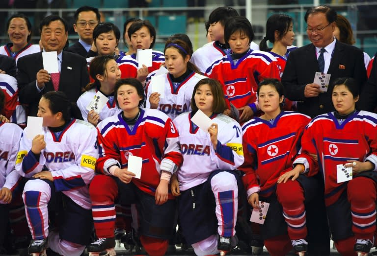 PyeongChang 2018 Organising Committee President Lee Hee-Beom (L top) poses with players from South Korea (white) and North Korea (red) after the IIHF women's world ice hockey championship match in Gangneung on April 6, 2017