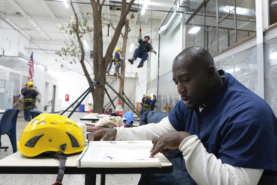 Prisoner Matthew McAfee studies climbing material at the Parnall Correctional Facility's Vocational Village in Jackson, Mich., Thursday, Dec. 1, 2022. McAfee is one of more than a dozen prisoners learning how to climb trees and trim branches around power lines as part of DTE Energy's $70 million plan to improve the utility's electric infrastructure. (AP Photo/Paul Sancya)