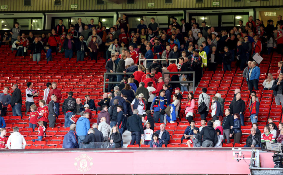Fans and players leave the pitch and North and West stands after an announcement to evacuate before the English Premier League match at Old Trafford in Manchester, England, on May 15, 2016. The match was later abandoned after a suspicious package was found in the stadium. (Martin Rickett/PA via AP)