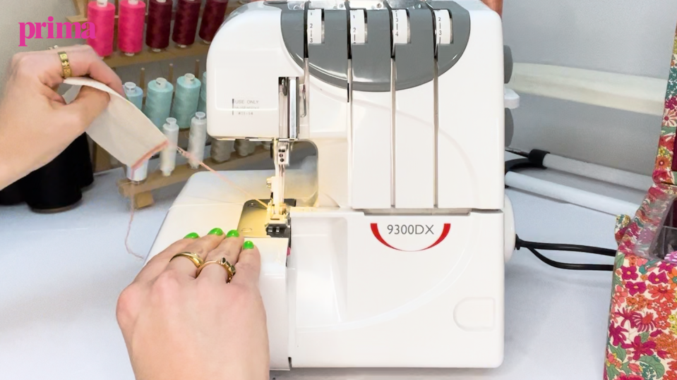 hands running fabric through overlocker sewing machine