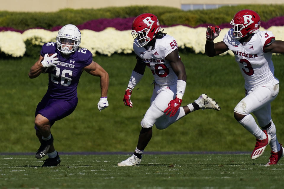 Northwestern running back Evan Hull, left, runs with the ball past Rutgers linebacker Mohamed Toure, center, and linebacker Tyreek Maddox-Williams during the first half of an NCAA college football game in Evanston, Ill., Saturday, Oct. 16, 2021. (AP Photo/Nam Y. Huh)