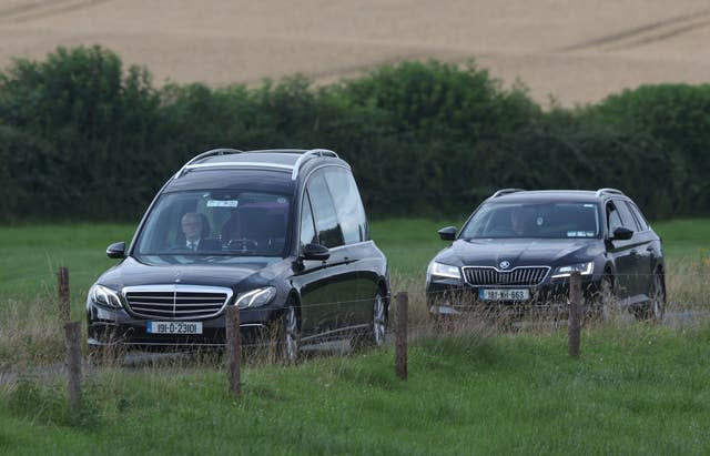 A hearse drives away from the crash scene