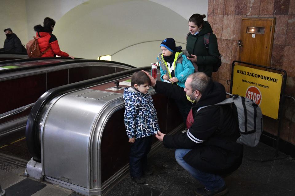 Alexander (R), reassures his son as the family takes refuge in a metro station in Kyiv in the morning of February 24, 2022. - Russian President Vladimir Putin announced a military operation in Ukraine on Thursday with explosions heard soon after across the country and its foreign minister warning a 