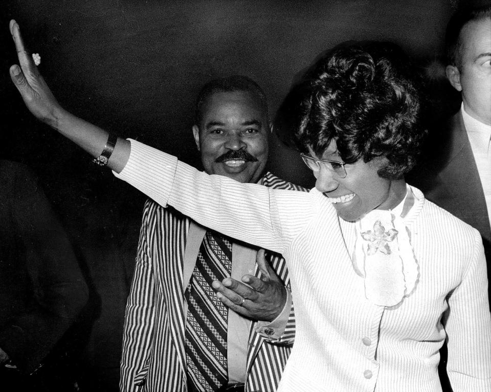 Shirley Chisholm waves as her husband stands behind her in a black and white photo. (Charles Ruppmann/NY Daily News Archive / Getty Images)