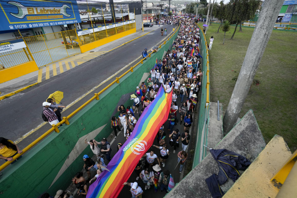 La gente marcha con una pancarta de arcoíris que marca el Desfile del Orgullo Gay anual en Quito, Ecuador, el sábado 22 de junio de 2024. (Foto AP/Dolores Ochoa)