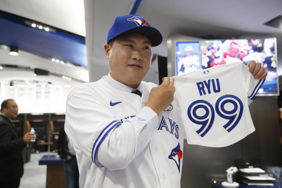 Toronto Blue Jays newly signed pitcher Hyun-Jin Ryu holds up a jersey for his expected baby following a news conference announcing his signing to the team in Toronto, Friday, Dec. 27, 2019. (Cole Burston/The Canadian Press via AP)