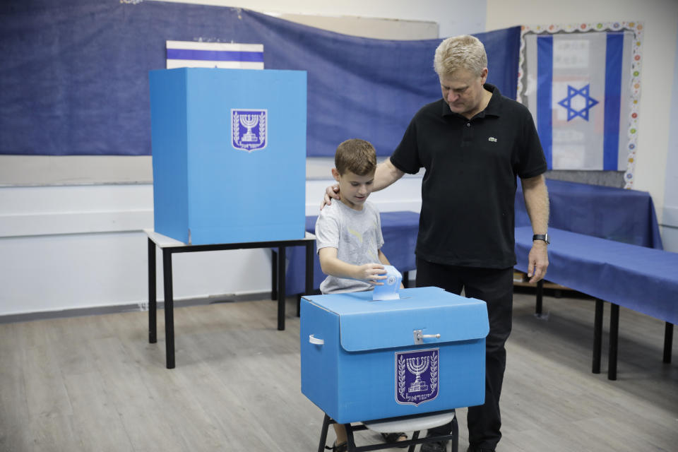 A man and his son vote at a polling station in Rosh Haayin, Israel, Tuesday, Sept. 17, 2019. Israelis began voting Tuesday in an unprecedented repeat election that will decide whether longtime Prime Minister Benjamin Netanyahu stays in power despite a looming indictment on corruption charges. (AP Photo/Sebastian Scheiner)