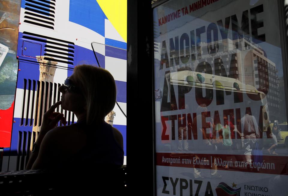 A woman waits at a bus stop with a poster for the radical left Syriza anti-austerity party that reads "We are opening the way to hope," as a tourist bus painted with the Greek flag passes by in Athens, Tuesday, June 12, 2012. Greece faces crucial national elections on Sunday, that could ultimately determine whether the debt-saddled, recession bound country remains in the eurozone. First elections on May 6 resulted in a hung parliament. (AP Photo/Petros Karadjias)